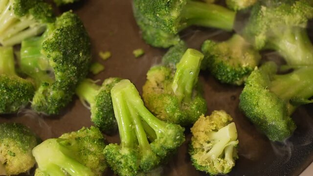 Skillet full of freshly cut broccoli cooking on the stove top - slow motion