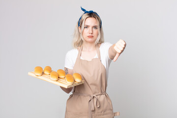 young pretty albino woman feeling cross,showing thumbs down with a bread buns tray