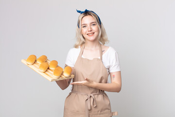 young pretty albino woman smiling cheerfully, feeling happy and showing a concept with a bread buns...