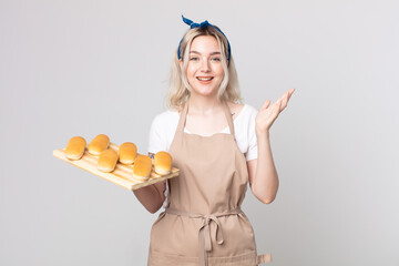 young pretty albino woman feeling happy, surprised realizing a solution or idea with a bread buns...