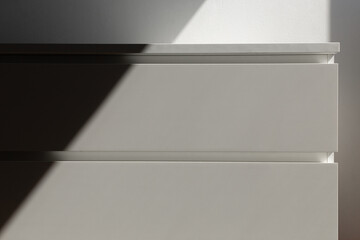 minimalistic white furniture chest of drawers without handles in the sunlight