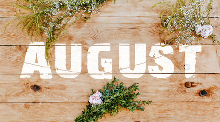 Text august on light wood decorated with plants and flowers. Wooden texture background mockup background