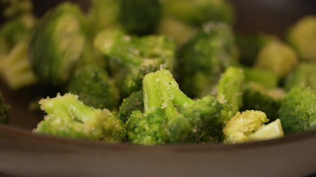 Skillet full of freshly cut broccoli cooking on the stove top - slow motion