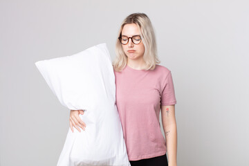 young pretty albino woman feeling sad, upset or angry and looking to the side wearing pajamas and...