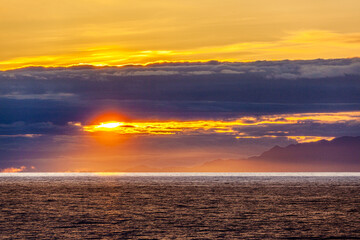 Fototapeta premium A sunset over the NW Pacific coast near Prince of Wales Island, Alaska, USA - Viewed from a cruise ship sailing the Inside Passage