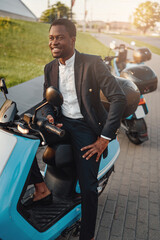 Positive black business person with scooter using his phone