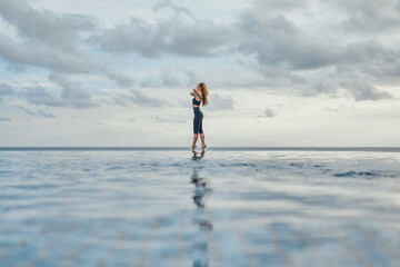 Fototapeta na wymiar Fitness woman posing against sky and endless sea