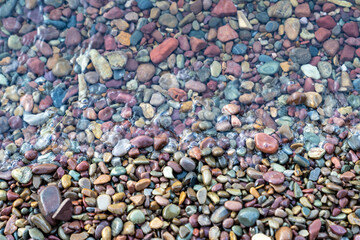 Brightly colored rocks and pebbles on the shores of Lake McDonald in Glacier National Park, in selective focus