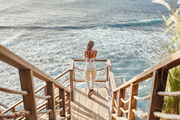 Woman with dreadlocks looking at sea waves in bali