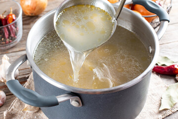 Saucepan with bouillon with a ladle. Bone broth