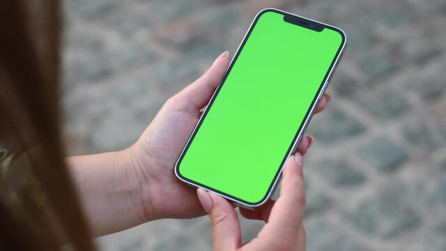 Women holding a phone in hands with green screen 
