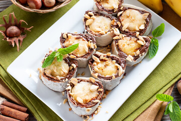 Delicious roll with banana slices on table. Banana roll with chocolate dessert