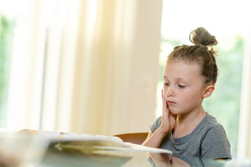 Mädchen, 6, sitzt unkonzentriert bei der Hausaufgabe