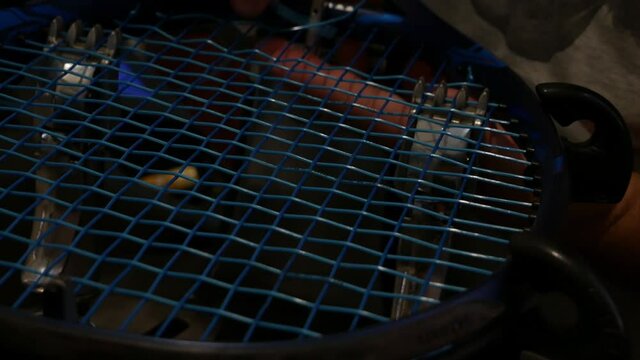 man's hands finish repairing the tennis racket