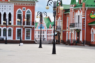 A street with houses of red and white brick with lanterns, without people. Russia Yoshkar Ola 01.05.2021. High quality photo