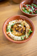 Close-up of a tasty hummus bowl with parsley and spices in a brown bowl