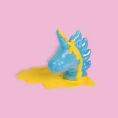 Creative idea made with blue painted unicorn head with yellow paint dripping on a pastel pink background.