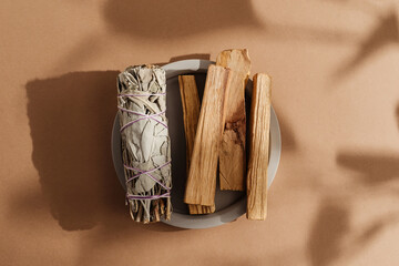 Branches of white sage, Palo Santo sticks tied in bunch on concrete plate, beautifully illuminated...