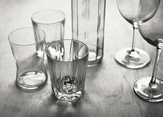 Stillleben aus unterschiedlichen transparenten einfachen Gläsern und einer Flasche aus Glas auf...