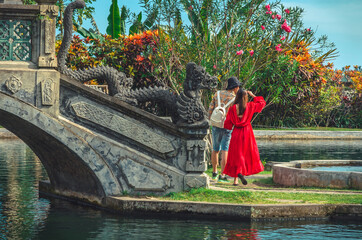 Young couple near the bridge with dragons in Water Palace Tirta Gangga in Bali island, Indonesia
