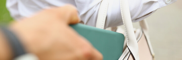 A man steals a wallet from a womans bag close up