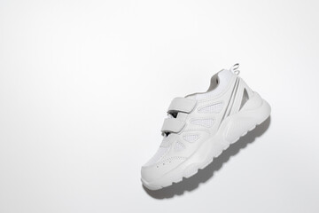 top view one white unisex running shoe on the side with hard shadows in the center isolated on a white background.