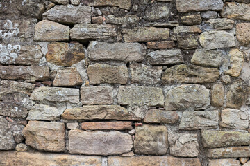 Gray rustic rocky wall built by many irregular stones.