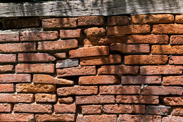 Naklejka premium Old brick wall with a wooden beam at the top.