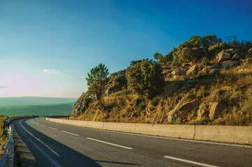 Country road passing on hilly landscape with rocks on sunset at the highlands of Serra da Estrela. The highest mountain range in continental Portugal.