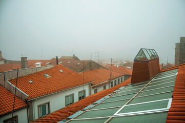 Close-up of shingles in roof on top of building, with glass skylight and morning mist at Guarda. A friendly and well-kept medieval town in Portugal.