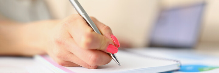 Womans hand taking notes with silver pen close-up