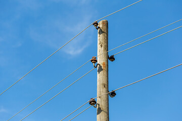 A wooden power line pole and steel electrical cables