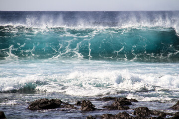 sea landscape, blue sea waves crashing against the rocks, big turquoise wave in the ocean
