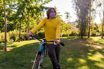 Man wearing face mask in the park with his bicycle