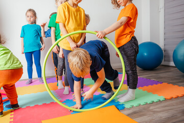 Curly girl crawling on colorful floor through hula hoops