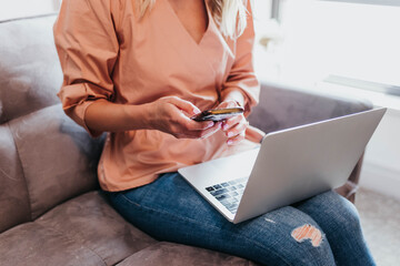 Close up of woman texting on cell phone with a computer on her lap