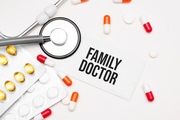 Stethoscope, pills and notebook with Family Doctor word on medical desk.