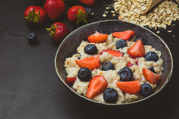 The concept of a healthy breakfast of oatmeal with strawberries and blueberries
