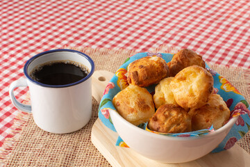 Minas Gerais cheese bread, hot, with a cup of black coffee, on a checkered picnic tablecloth