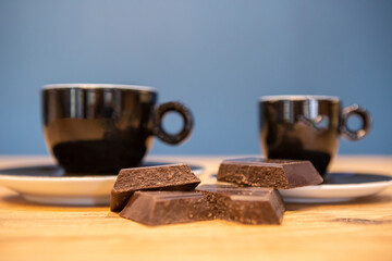 Dark chocolate pieces and coffee on a wooden table