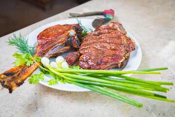 Cooked fried meat with spices on a white plate. Oven-baked meat for dinner with a glass of red wine. Close-up