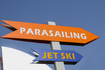 Orange And Blue Directional Arrow-shaped Signpost For Parasailing And Jet ski On The Beach.