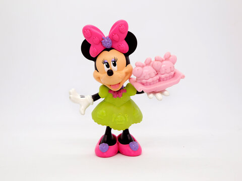 Minnie Mouse. Toy. Cartoon characters from Walt Disney Pictures Studios. Minnie is Mickey Mouse's girlfriend. Green dress. Doll with interchangeable clothes.  Minnie with a cake in hand. Plastic toys.