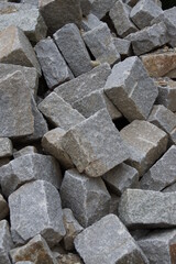 Aus harten Gestein hergestellte Bausteine mit identischen Abmessungen warten auf einer Baustelle darauf, dass sie eingebaut werden.