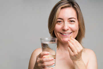 Happy mature woman taking a collagen pill