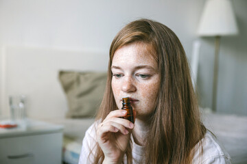 Young woman is sniffing essential oil. Loss of smell and taste from Covid