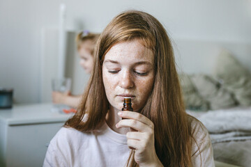 Young woman is sniffing essential oil. Loss of smell and taste from Covid	