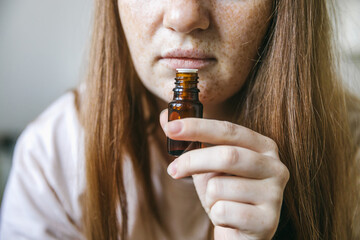 Young woman is sniffing essential oil. Loss of smell and taste from Covid