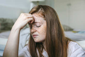 A young woman suffers from a headache, migraine. Consequences of covid