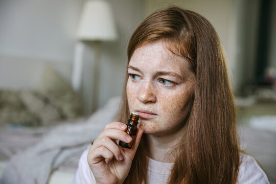 Young woman is sniffing essential oil. Loss of smell and taste from Covid
